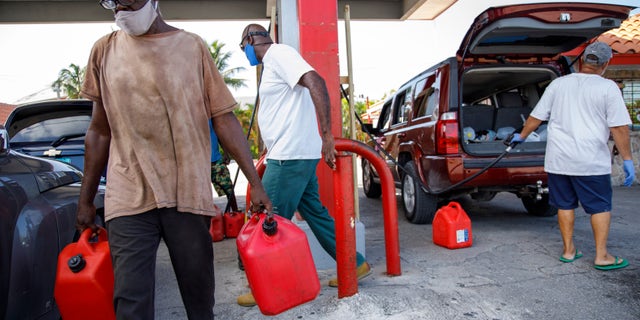 A resident walks with containers filled with gasoline at Cooper's gas station before the arrival of Hurricane Isaias in Freeport, Grand Bahama, Bahamas, Friday, July 31, 2020. (AP Photo/Tim Aylen)