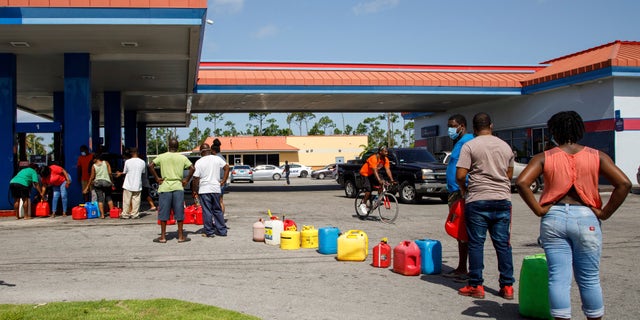 Residents wait in line to fill their containers with gasoline before the arrival of Hurricane Isaias in Freeport, Grand Bahama, Bahamas, Friday, July 31, 2020. (AP Photo/Tim Aylen)