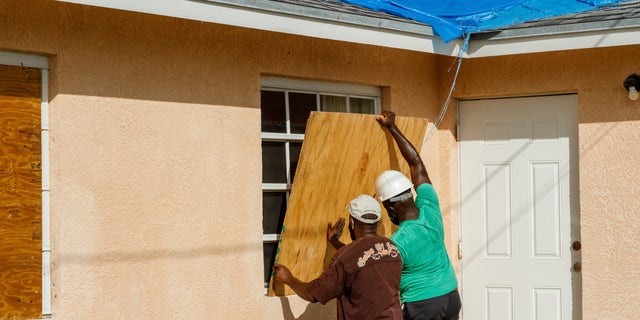 Residents cover a window with plywood in preparation for the arrival of Hurricane Isaias, in the Heritage neighborhood of Freeport, Grand Bahama, Bahamas, Friday, July 31, 2020. (AP Photo/Tim Aylen)