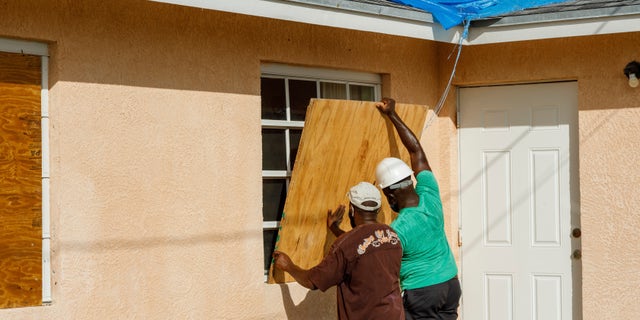 Residents cover a window with plywood in preparation for the arrival of Hurricane Isaias, in the Heritage neighborhood of Freeport, Grand Bahama, Bahamas, Friday, July 31, 2020. (AP Photo/Tim Aylen)