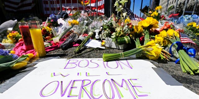 FILE - In this April 17, 2013 photograph, flowers and signs adorn a barrier, two days after two explosions killed three and injured hundreds, at Boylston Street near the of finish line of the Boston Marathon at a makeshift memorial for victims and survivors of the bombing. A federal appeals court has overturned the death sentence of Dzhokhar Tsarnaev in the 2013 Boston Marathon bombing, Friday, July 31, 2020, saying the judge who oversaw the case didn't adequately screen jurors for potential biases. (AP Photo/Charles Krupa, File)