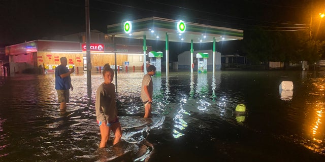 People walk on the flooded Sea Mountain Highway in North Myrtle Beach, S.C., as Isaias neared the Carolinas on Monday night, Aug. 3, 2020. (Jason Lee/The Sun News via AP)