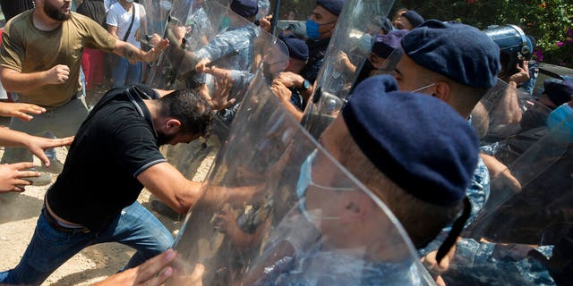 Riot police scuffle with anti-government protesters outside the Ministry of Energy and Water in Beirut, Lebanon, Tuesday, Aug. 4, 2020.  (AP Photo/Hassan Ammar)