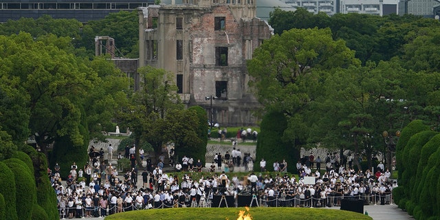 Visitors observe a minute of silence for the victims of the atomic bombing, at 8:15am, the time atomic bomb exploded over the city, at the Hiroshima Peace Memorial Park during the ceremony to mark the 75th anniversary of the bombing Thursday, Aug. 6, 2020, in Hiroshima, western Japan. (AP Photo/Eugene Hoshiko)