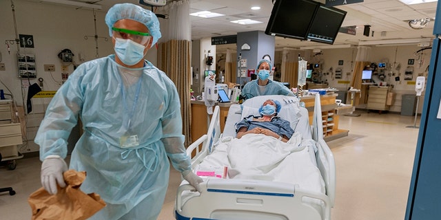 In this July 2020, photo released by Brigham and Women's Hospital, members of the transplant anesthesiology team, Drs. Kamen V. Vlassakov and Lindsay Wahl lead Carmen Blandin Tarleton to the operating room for her second face transplant at Brigham and Women's Hospital in Boston.