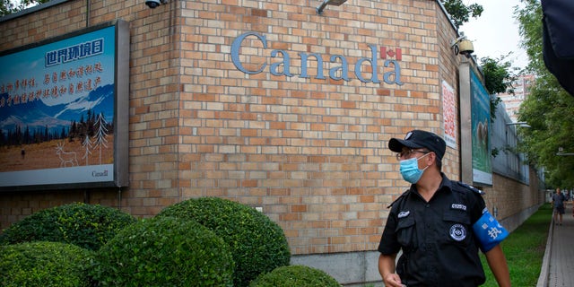 A security officer wearing a face mask to protect against the coronavirus stands outside the Canadian Embassy in Beijing, Thursday, Aug. 6, 2020. China announced on Friday that it had sentenced a Canadian to death on drug charges, the second day in a row Chinese courts handed down the death penalty to a Canadian citizen. (AP Photo/Mark Schiefelbein)