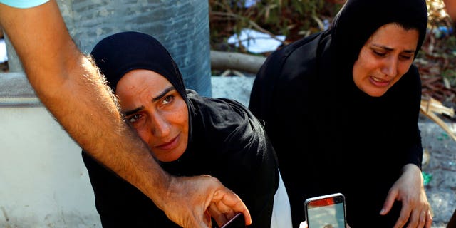 Zeinab Zer Eldin, left, and her sister-in-law show a photo of her missing husband on Friday, Aug. 7, near the site of the explosion. (AP Photo/Thibault Camus)