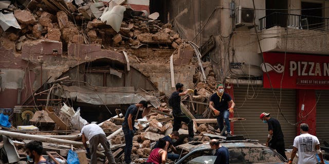 People remove debris from a house damaged by Tuesday's explosion in the seaport of Beirut, Lebanon, Friday, Aug. 7, 2020. Rescue teams were still searching the rubble of Beirut's port for bodies on Friday, nearly three days after the massive explosion sent a wave of destruction through Lebanon's capital. (AP Photo/Felipe Dana)