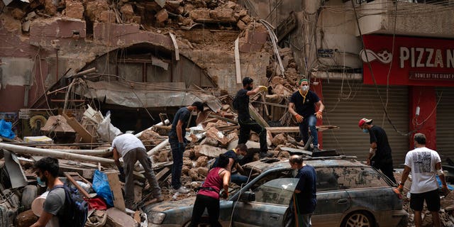 People remove debris from a house damaged by Tuesday's explosion in the seaport of Beirut, Lebanon, Friday, Aug. 7, 2020. Rescue teams were still searching the rubble of Beirut's port for bodies on Friday, nearly three days after the massive explosion sent a wave of destruction through Lebanon's capital. (AP Photo/Felipe Dana)