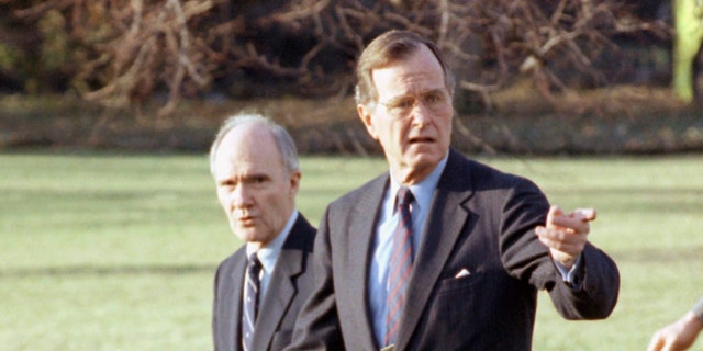 In this Feb. 6, 1990 file photo, President George H. W. Bush gestures as he and National Security Adviser Brent Scowcroft walk to the presidential helicopter on the South Lawn of the White House in Washington. (AP Photo/Barry Thumma)