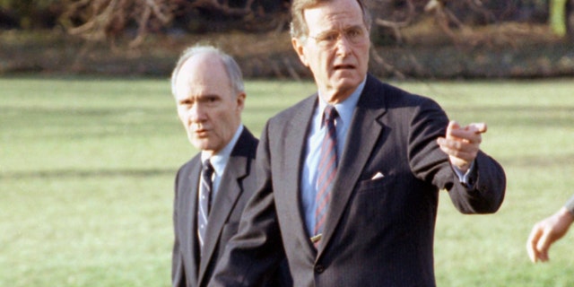 In this Feb. 6, 1990 file photo, President George H. W. Bush gestures as he and National Security Adviser Brent Scowcroft walk to the presidential helicopter on the South Lawn of the White House in Washington. (AP Photo/Barry Thumma)