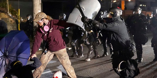 A Portland police officer shoves a protester as police try to disperse the crowd in front of the Multnomah County Sheriff's Office early in the morning on Saturday, Aug. 8, 2020 in Portland, Ore. (Associated Press)