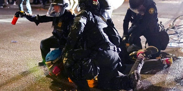 Portland police officers make an arrest while dispersing protesters in front of the Multnomah County Sheriff's Office early in the morning on Saturday, Aug. 8, 2020 in Portland, Ore. (AP Photo/Nathan Howard)