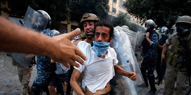A protestor is evacuated from clashes during a protest against the political elites and the government after this week's deadly explosion at Beirut port which devastated large parts of the capital in Beirut, Lebanon, Saturday, Aug. 8, 2020. (AP Photo/Thibault Camus)