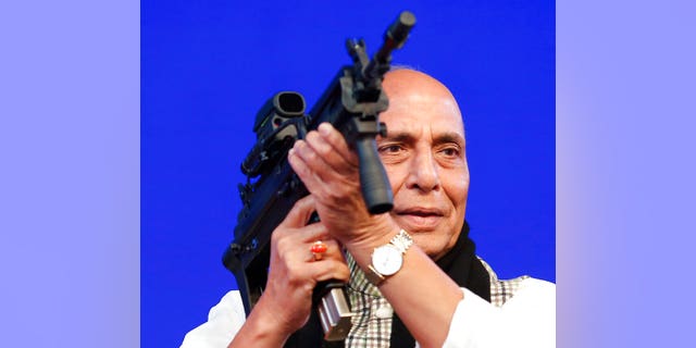 FILE- In this Feb. 7, 2020 file photo, Indian Defense Minister Rajnath Singh holds a model of a light machine gun during DefExpo20 in Lucknow, India. India will ban the imports of 101 items of military equipment in an effort to boost indigenous production and improve self-reliance in weapons manufacturing, Singh said Sunday. (AP Photo/Rajesh Kumar Singh, File)