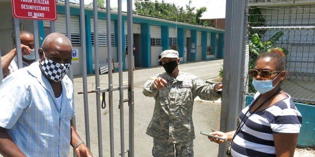An official turns away two voters at a voting center lacking ballots in Carolina, Puerto Rico, Sunday, Aug. 9, 2020. Puerto Rico's primaries were marred on Sunday by a lack of ballots in a majority of centers across the U.S. territory, forcing frustrated voters who braved a spike in COVID-19 cases to turn around and go back home. 