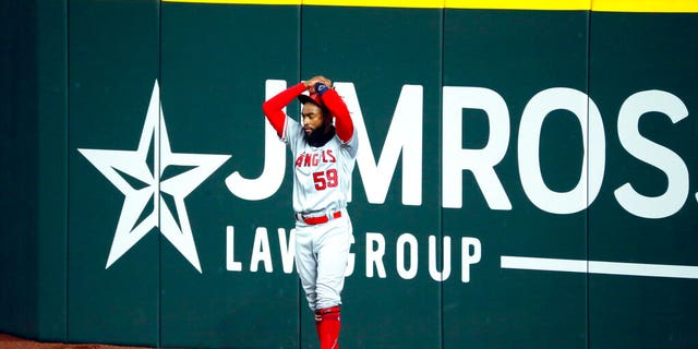 Los Angeles Angels right fielder Jo Adell puts his hands on his head after a fly ball by Texas Rangers' Nick Solak popped out of his glove and over the right field wall for a solo home run during the fifth inning of a baseball game in Arlington, Texas, Sunday, Aug. 9, 2020.