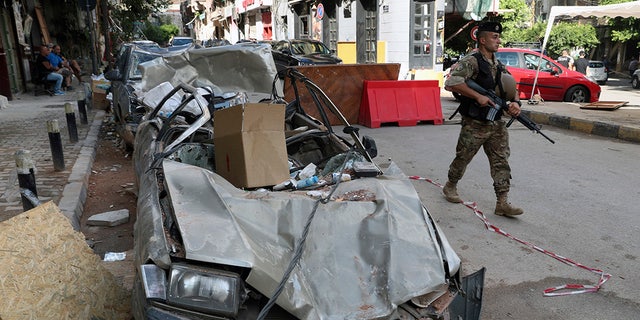 A soldier walks past damaged vehicles, Monday, Aug. 10, 2020, in Beirut, Lebanon, near the site of last week's explosion that hit the city's seaport. (AP Photo/Bilal Hussein)