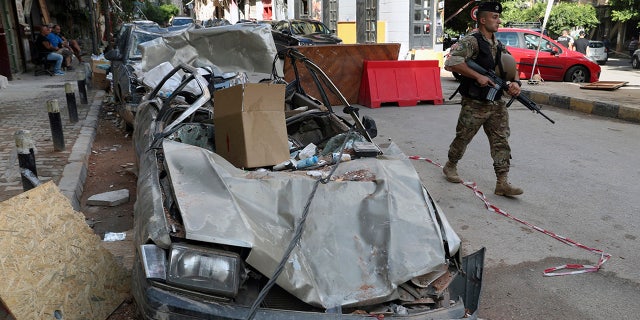 A soldier walks past damaged vehicles, Monday, Aug. 10, 2020, in Beirut, Lebanon, near the site of last week's explosion that hit the city's seaport. (AP Photo/Bilal Hussein)