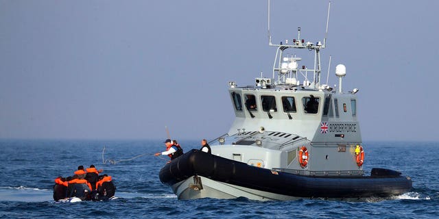 A Border Force vessel assisting a group of people believed to be emigrating aboard from their inflatable tricycle in Channel, Monday, August 10, 2020. (Gareth Fuller / PA via AP)