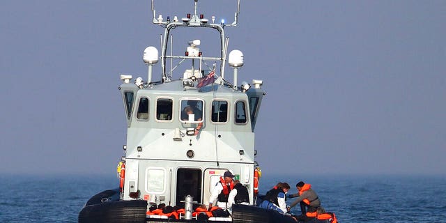 A Border Force vessel assist a group of people thought to be migrants on board from their inflatable dinghy in the Channel, Monday Aug. 10, 2020.(Gareth Fuller/PA via AP)