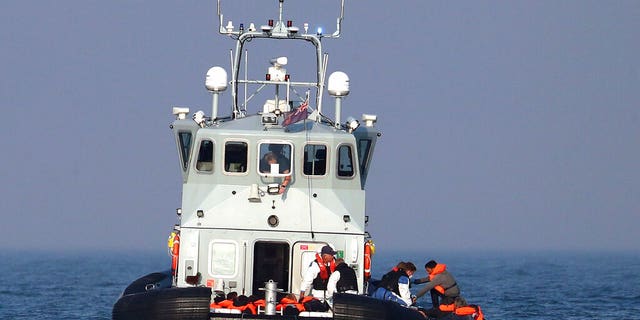 A Border Force vessel assist a group of people thought to be migrants on board from their inflatable dinghy in the Channel, Monday Aug. 10, 2020.(Gareth Fuller/PA via AP)