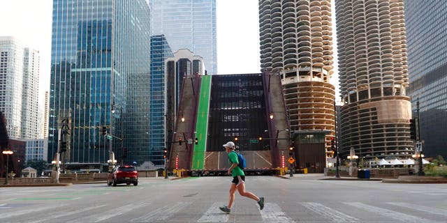 A jogger passes Monday, Aug. 10, 2020, the raised Dearborn Street bridge over the Chicago river after overnight vandalism in Chicago. 