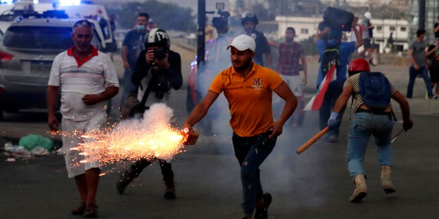 Anti-government protesters use fireworks against Lebanese riot police during a protest in the aftermath of last Tuesday's massive explosion. (AP Photo/Hassan Ammar)
