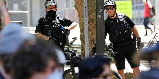 July 20, 2020: Police officers look on at protesters in Seattle. (AP Photo/Elaine Thompson)