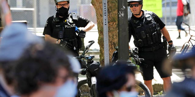 FILE: Police officers look on at protesters in Seattle. 