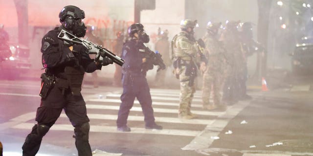 FILE - In this July 28, 2020, file photo, Federal officers deploy tear gas and crowd-control munitions at demonstrators during a protest at the federal courthouse in Portland, Ore. (AP Photo/Marcio Jose Sanchez, File)