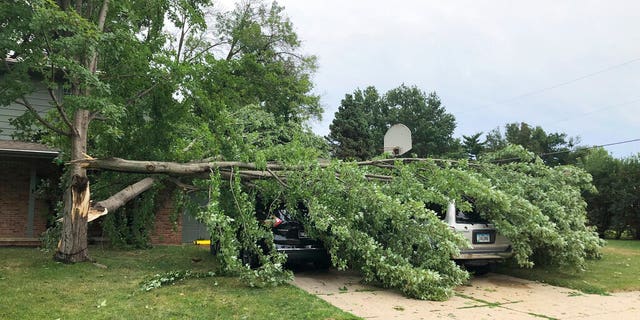 A tree fell across vehicles at a home in West Des Moines, Iowa, after a severe thunderstorm moved across Iowa on Monday Aug. 10, 2020, downing trees, power lines and damaging buildings. 