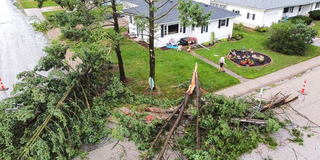 Downed trees and a utility pole in front of the home of Tim and Patricia Terres in Walcott, Iowa after high winds and heavy rain passed through the area Monday, Aug. 10, 2020, in Davenport, Iowa. 