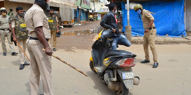 A policeman thrashes a motorist for violating prohibitory orders a day after violent protests in Bengaluru, India, Wednesday, Aug. 12, 2020. (AP Photo)