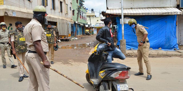 A policeman thrashes a motorist for violating prohibitory orders a day after violent protests in Bengaluru, India, Wednesday, Aug. 12, 2020. (AP Photo)