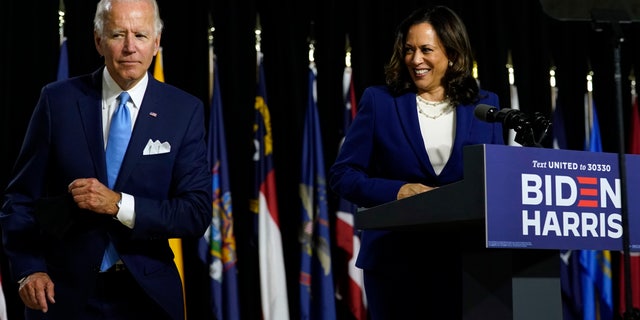 Democratic presidential candidate former Vice President Joe Biden gets his face mask from the podium before his running mate Sen. Kamala Harris, D-Calif., speaks during a campaign event at Alexis Dupont High School in Wilmington, Del., Wednesday, Aug. 12, 2020. (AP Photo/Carolyn Kaster)