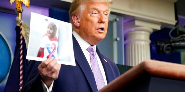 President Donald Trump holds a photo of LeGend Taliferro as he speaks at a news conference in the James Brady Press Briefing Room at the White House, Thursday, Aug. 13, 2020, in Washington. (AP Photo/Andrew Harnik)