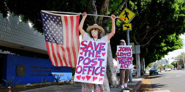 Erica Koesler, left, and David Haerle, both of Los Angeles, demonstrate outside a USPS post office, Saturday, Aug. 15, 2020, in the Los Feliz section of Los Angeles. (AP Photo/Chris Pizzello)