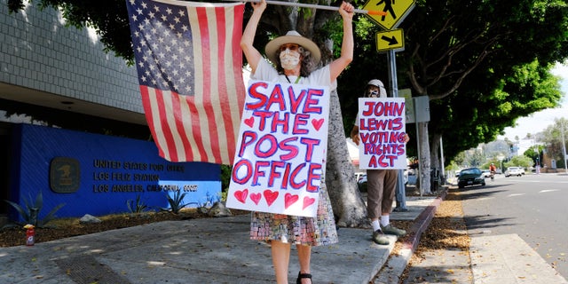 Erica Koesler, left, and David Haerle, both of Los Angeles, demonstrate outside a USPS post office, Saturday, Aug. 15, 2020, in the Los Feliz section of Los Angeles. (AP Photo/Chris Pizzello)