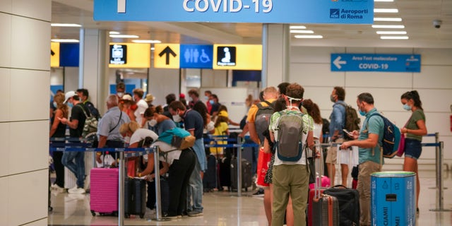 Vacationers arriving in Rome from four Mediterranean countries line up with their suitcases at Rome's Leonardo da Vinci airport to be immediately tested for COVID-19, Sunday, Aug.16, 2020. (AP Photo/Andrew Medichini)