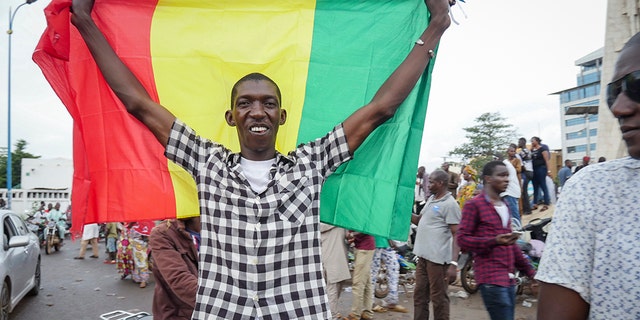 A man holds a national flag as he celebrates with others in the streets in the capital Bamako, Mali Tuesday, Aug. 18, 2020. Mutinous soldiers detained Mali's president and prime minister Tuesday after surrounding a residence and firing into the air in an apparent coup attempt after several months of demonstrations calling for President Ibrahim Boubacar Keita's ouster. (AP Photo)