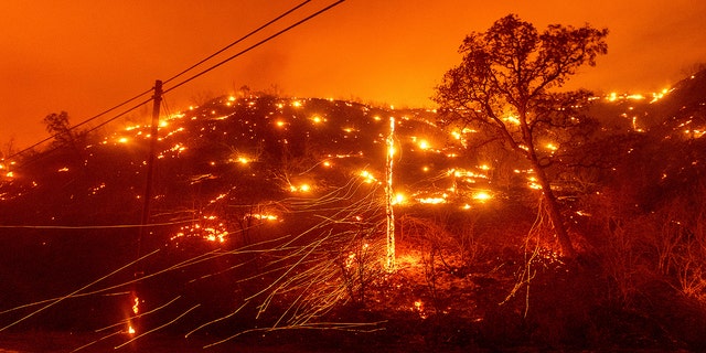 Seen in a long-exposure photograph, embers burn along a hill as fires at the LNU Lightning Complex tear through the unincorporated county of Napa, Calif. On Tuesday, August 18, 2020. Fire crews from across the region have rushed to contain dozens of forest fires triggered by lightning strikes as a heat wave continues statewide.  (AP Photo / Noah Berger)