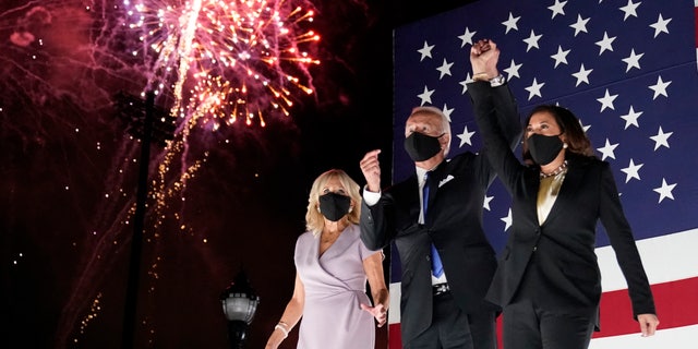Democratic presidential candidate former Vice President Joe Biden and his running mate Sen. Kamala Harris, D-Calif., join hands as they watch fireworks during the fourth day of the Democratic National Convention, Thursday, Aug. 20, 2020, at the Chase Center in Wilmington, Del. Jill Biden is at left. (AP Photo/Andrew Harnik)
