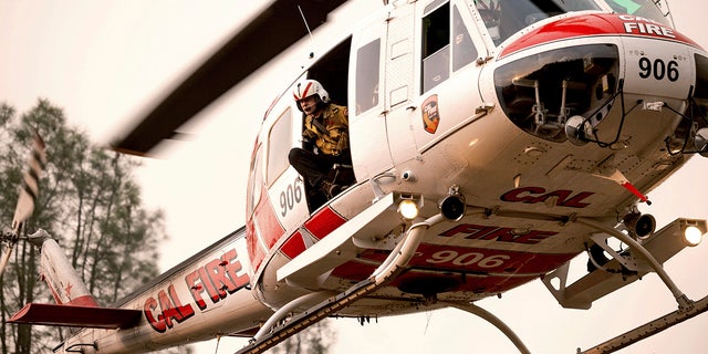 A Howard Forest Helitack firefighter looks out from a helicopter while battling the LNU Lightning Complex on Sunday, Aug. 23, 2020, in unincorporated Lake County, Calif. (AP Photo/Noah Berger)