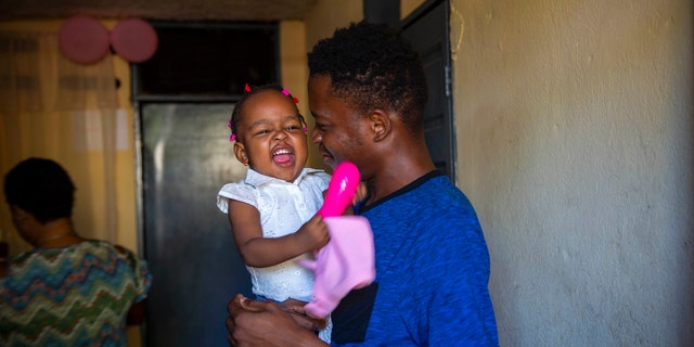 A man holds up his 1-year-old daughter at his house in Port-au-Prince, Haiti, Tuesday, Aug. 25, 2020. (Associated Press)