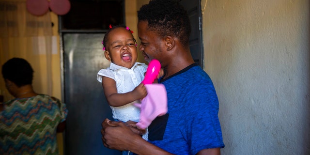 A man holds up his 1-year-old daughter at his house in Port-au-Prince, Haiti, Tuesday, Aug. 25, 2020. (Associated Press)