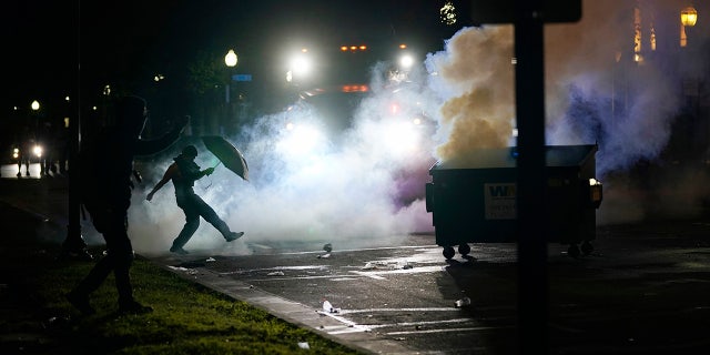 A protester kicking a smoke canister Tuesday in Kenosha, Wis. Anger over the Sunday shooting of Jacob Blake, a Black man, by police spilled into the streets for a third night. (AP Photo/Morry Gash)