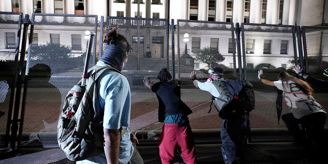 People trying to push over protective fencing Tuesday in Kenosha. (AP Photo/Morry Gash)