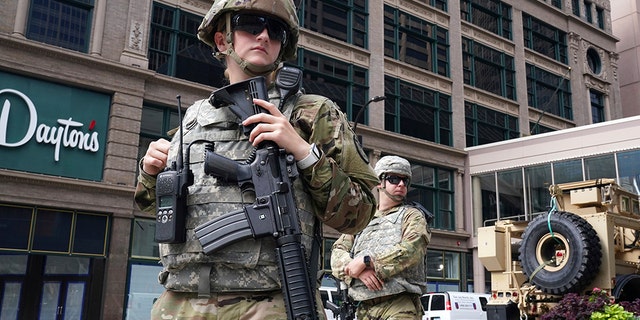 Members of the Minnesota National Guard stand at the intersection of South 7th Street and Nicollet Mall in Minneapolis, Thursday, Aug. 27, 2020, as community members and business owners clean up damage from looters.  (Anthony Souffle/Star Tribune via AP)