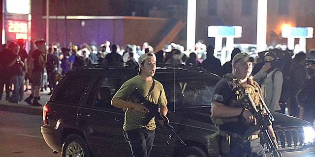 Kyle Rittenhouse, left, with backwards cap, walks along Sheridan Road in Kenosha, Wis. on Tuesday with another armed civilian. Prosecutors on Thursday charged Rittenhouse, a 17-year-old from Illinois in the fatal shooting of two protesters and the wounding of a third in Kenosha, Wisconsin, during a night of unrest following the weekend police shooting of Jacob Blake. (Adam Rogan/The Journal Times via AP)
